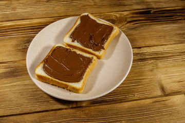 Two slices of bread with delicious chocolate hazelnut spread on wooden table