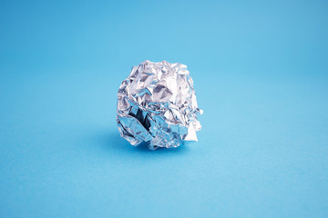 Lump of Aluminium foil on blue background. Metal crumpled foil.