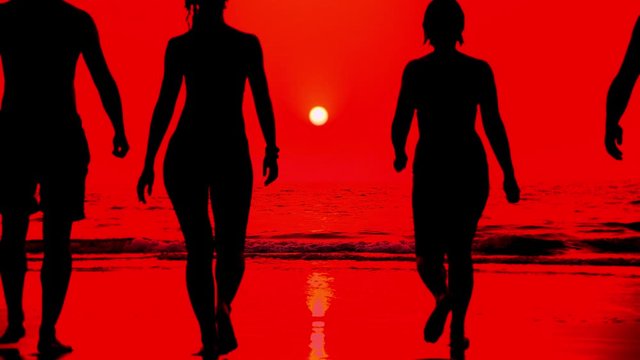 The silhouette of four people, two men and two women who enter the sea and dive during a bloody sunset. Stylish color correction silhouettes of people against the sun and red sky in slow motion.