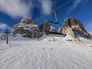 Obraz premium Ski lift with chair and skiers in front of mountain with snow and blue sky