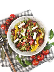 vegetable salad with sun-dried tomatoes and soft cheese on a white background isolated top view