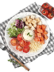 Caesar salad with red fish laid out according to the ingredients on a light plate on a white background isolated top view
