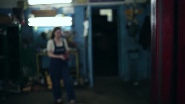 The concept of gender equality. A pretty young woman in a work uniform, working at the machine, the frame blurs, and then comes and wipes his hands, tired face close-up. Work in an auto repair shop
