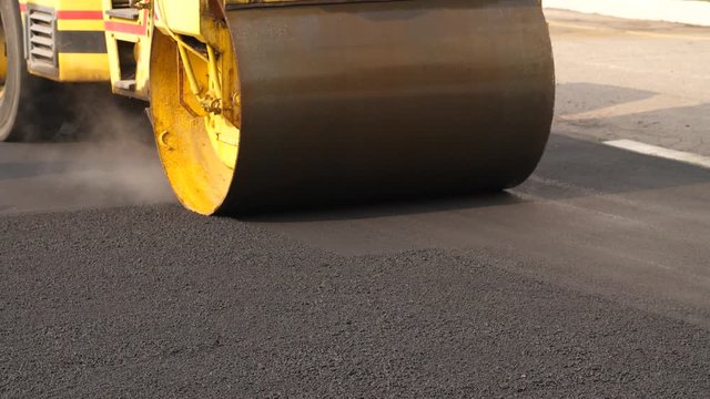 Workers stacking asphalt with roller