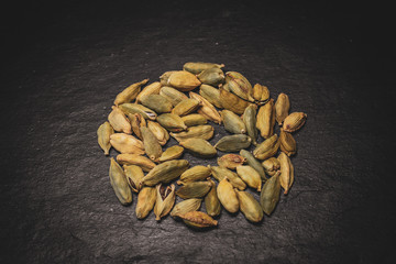 Macro view of green cardamom seeds on slate background. Spices of the world. 