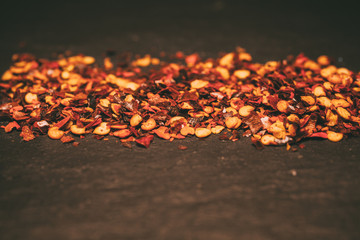 Close up of red chili flakes on black slate background. Crushed cayenne pepper.  