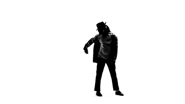 Silhouette of a young man dancer dancing in style Michael Jackson on white background. Close up, slow motion.