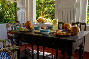 wooden table is covered with healthy variety of natural food, banana porridge, scrambled eggs, omelet with vegetables, coconut, dragon's eye