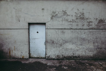 Grungy worn out metallic door in the wall of an old prison of the communist Romanian Securitate.