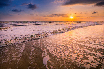 Fototapeta na wymiar Beautiful cloudscape over the sea with soft wave of blue ocean on sandy beach during sunrise.