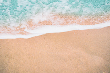 Fototapeta na wymiar Top view soft wave and white foam of ocean on sand beach. (Selective focus)