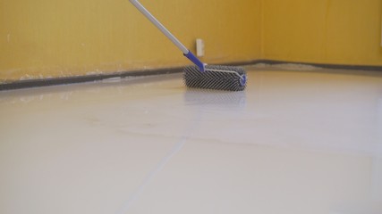 finishing work - a working roller primers the floor before pouring the floor. Workers poured into...