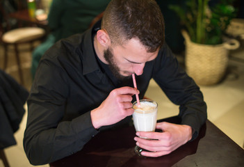 man drinks milk shake with straw in a cafe