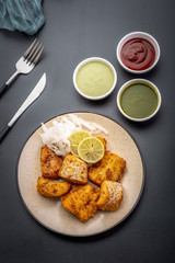 Boneless fried fish served with green sauce and dip