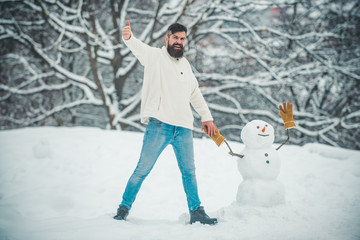 Handsome bearded man, father in winter clothes. Handsome Winter Man with snowman in frosty winter...