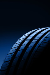 Car tire on black background. Toning in trendy color 2020 classic blue.