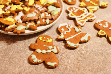 Plate with tasty festive homemade gingerbread cookies in shape of christmas tree and smiling gingerbread man on grey grunge table.