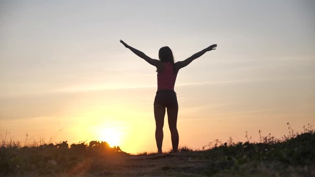 Happy woman jumping on beach enjoying sunset on summer travel vacation holiday. Happiness and bliss concept video with female jumping of joy celebrating in silhouette. SLOW MOTION 4k
