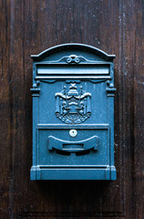 Closeup of antique style blue mailbox hanging on wooden door