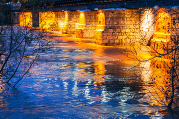 illuminated stone bridge over the river at night