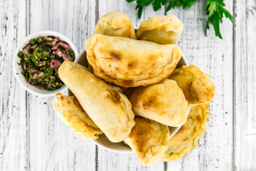 Some Empanadas on a vintage wooden table (selective focus; close-up shot)