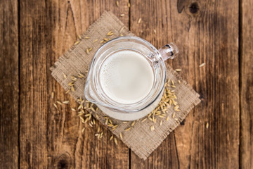 Portion of healthy Oat Milk on an old wooden table (selective focus; close-up shot)