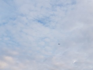 Tiny airplane on a vast cloudy sky