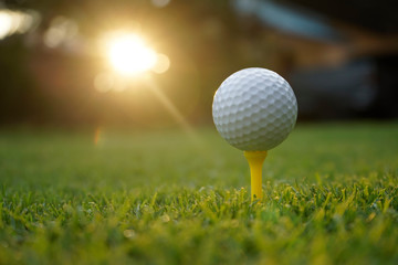 Golf ball on tee in beautiful golf course at sunset background.
