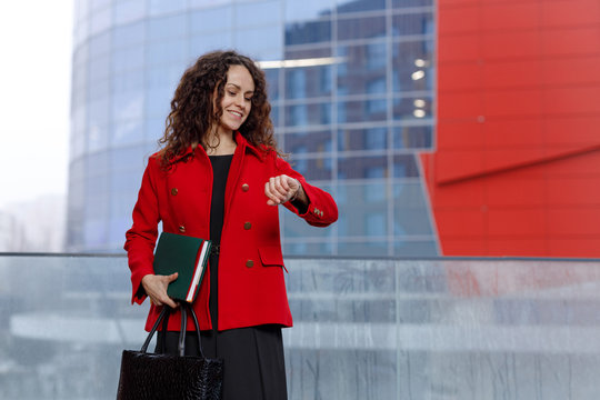 Horizontal portrait of a attractive business woman, in red suit, coming on a job, look at the time. Business content.