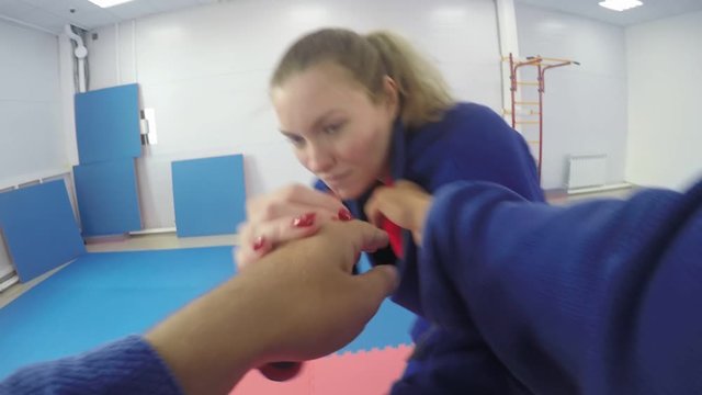POV shot of male martial arts athlete greeting female opponent and start sparring with her while practicing jujutsu in gym