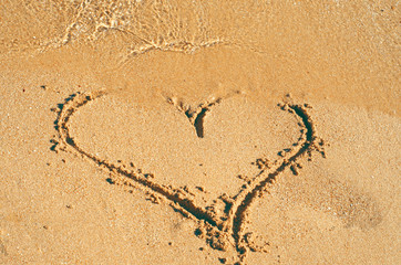 Heart shape drawing in the sand, sea on the beach