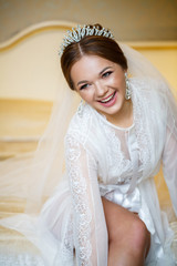 bride puts on white shoes on the wedding day