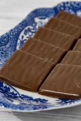 Chocolate mint wafers on a patterned blue and white plate.  Grey wood background