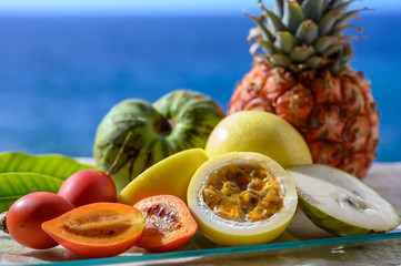 Fresh ripe yellow  passion fruit, cherymoia and tamarillo on blue sea background