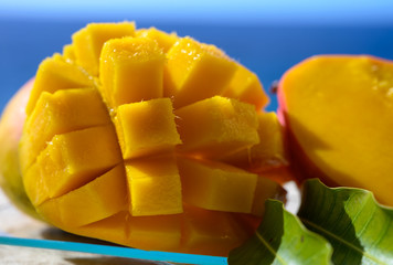 Fresh ripe sweet yellow mango fruit served on glass plate with blue seaview background