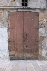 Old closed wooden door and padlock, closeup. Stone wall. Peeling paint.