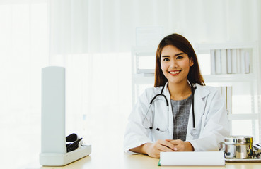 Portrait of a asian beautiful female doctor She was sitting at the desk and smiling happily.