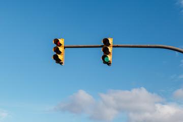 dos semaforos en un solo poster con el cielo azul con nubes de fondo. luces roja, verde y amarilla....