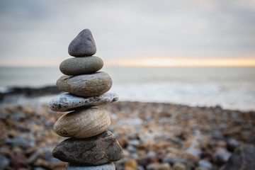 Fototapeta na wymiar Stack of stones against blurred seascape on a beach swansea wales, space for text. Zen concept