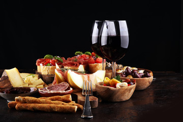 Italian antipasti wine snacks set. Cheese variety, Mediterranean olives, seafood salad, Prosciutto di Parma, tomatoes, anchovy and wine in glasses