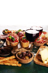 Italian antipasti wine snacks set. Cheese variety, Mediterranean olives, seafood salad, Prosciutto di Parma, tomatoes, anchovy and wine in glasses