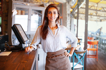 Waist portrait of waitress registrated orders to the payment terminal. Young and beautiful waitress...
