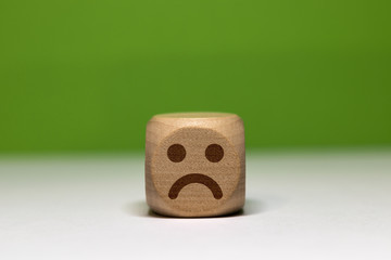 Pictogramme smiley triste sur cube en bois