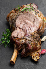Whole roast lamb leg on black stone background © lena_zajchikova