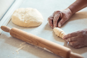 Female hands rolling dough into rolls. Process of making croissant rolls