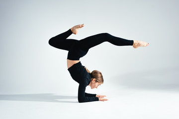 Young handsome fit woman wearing black sportswear doing stretching body against white background....