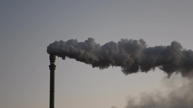 Dark hot smoke coming out of an industrial chimney of a chemical plant. Air pollution and global warming