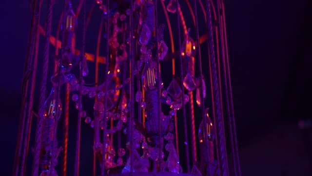 Old crystal chandelier with a metal frame in a night club in the spotlights light shimmers with blue and pink light giving glare