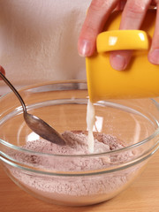 Pouring milk into frosting mixture. Making frosting. Making Chocolate Layer Cake with Cream Cheese...