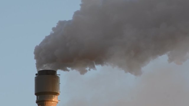 Dark hot smoke coming out of an industrial chimney of a chemical plant. Air pollution and global warming